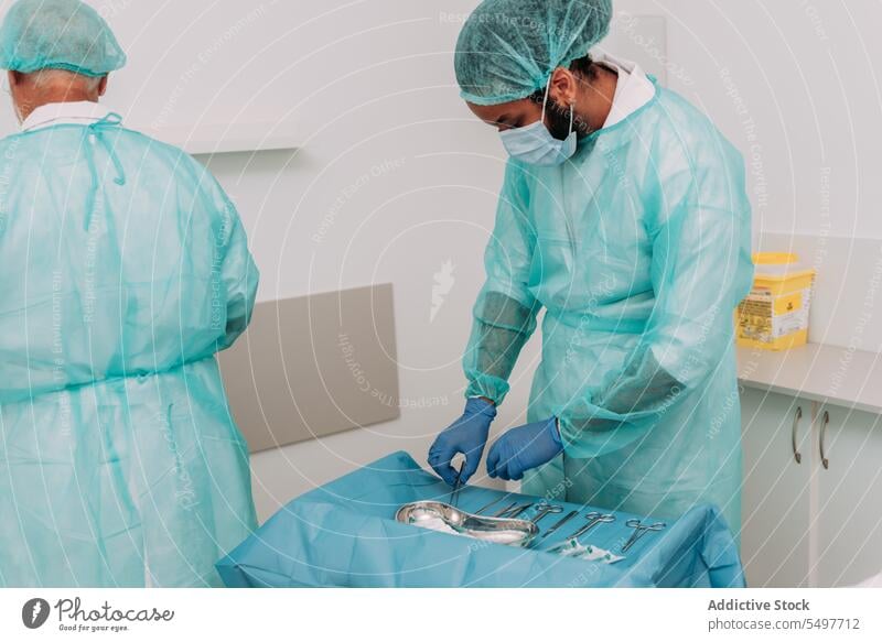 Ethnischer männlicher Arzt legt chirurgische Instrumente auf den Tisch neben dem Arzt Männer Chirurgie Assistent vorbereiten Operationssaal Zusammensein Klinik