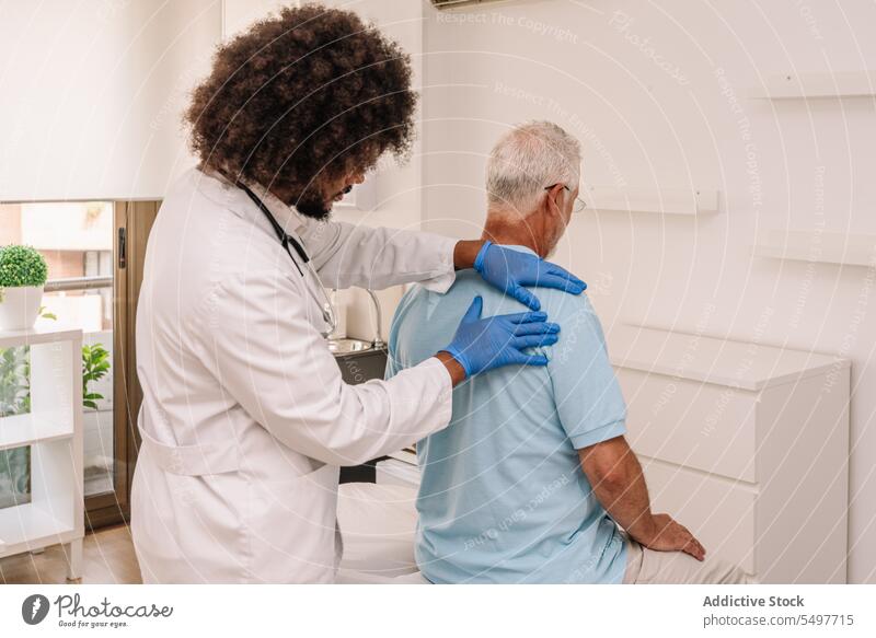 Lockenhaariger Arzt bei der Untersuchung eines Patienten Männer geduldig untersuchen professionell Stethoskop Krankenhaus Gesundheitswesen Diagnostik Klinik