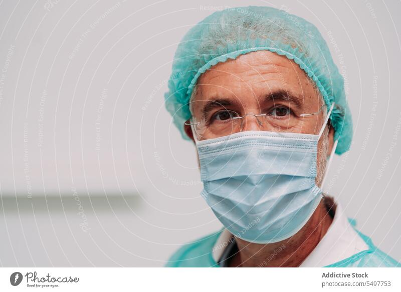 Männlicher Chirurg in der Klinik stehend Mann Arzt Glück Sanitäter Gesundheitswesen Porträt Krankenhaus Uniform professionell männlich reif Mundschutz