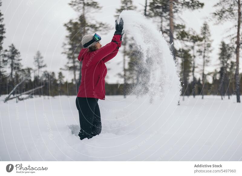 Unbekannte Frau spielt mit Schnee Winter werfen kalt Baum Oberbekleidung Natur Saison spielen Wetter Winterzeit Aktivität Umwelt Spaß haben Lappland spielerisch