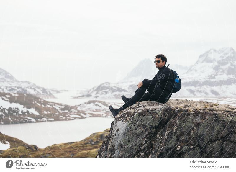 Mann sitzt auf einer Felskante und genießt die Berglandschaft Berge u. Gebirge Reisender felsig Natur Hochland Winter bewundern Saum Gelände männlich Ambitus