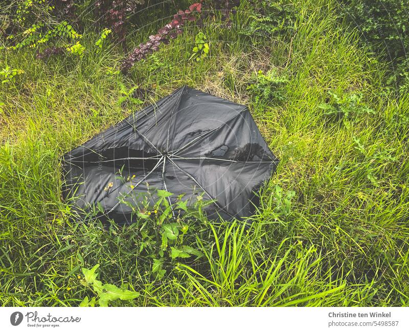 unverkäuflich | kaputter schwarzer Regenschirm am Rande einer Autobahnraststätte kaputter Regenschirm Böschung Grünstreifen Müll entsorgt wegwerfen weggeworfen