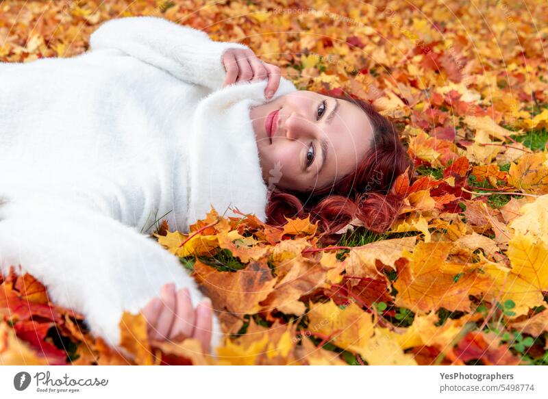 Frauenporträt umgeben von Herbstblättern. Frau auf dem Boden sitzend im Freien allein schön Schönheit hell lässig Farbe farbenfroh genießen fallen Laubwerk