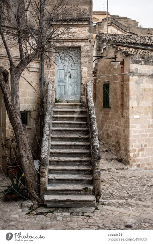 Verlassene Treppe, die zu einer geschlossenen Tür in der typisch italienischen Stadt Matera, Süditalien, führt Treppenhaus malerisch Baum Haus alt Stein blau