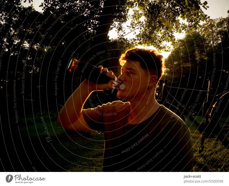 Junger Mann lässt den Sonnentag mit einem Bier ausklingen Sommer Genuss Gegenlicht Silhouette trinken Durst Alkohol genießen Erfrischung Hintergrund neutral
