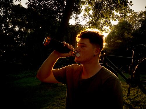 Junger Mann lässt den Sonnentag mit einem Bier ausklingen Sommer Genuss Gegenlicht Silhouette trinken Durst Alkohol genießen Erfrischung Hintergrund neutral