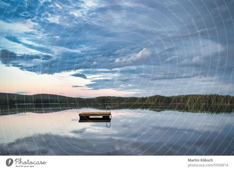 Schwimmende Insel in Schweden auf einem See bei Sonnenuntergang. Die Wolken spiegeln sich im Wasser. Schwimminsel Holzinsel Reflexion & Spiegelung Sommerurlaub