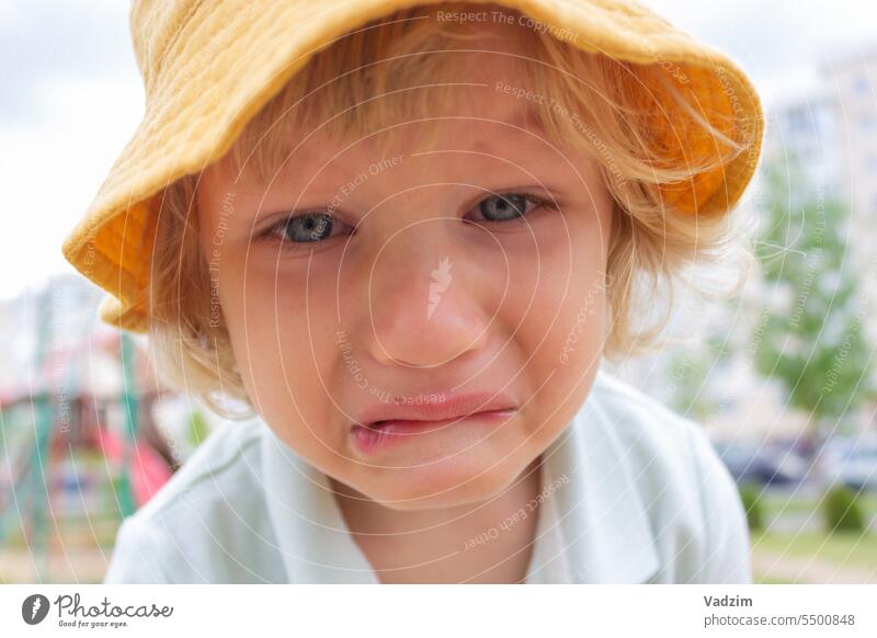 Die Stimmung des Kindes. Ein kleiner trauriger Junge mit einem gelben Panamahut weint auf der Straße. Familie Menschen Kinder Kaukasier Spaziergang