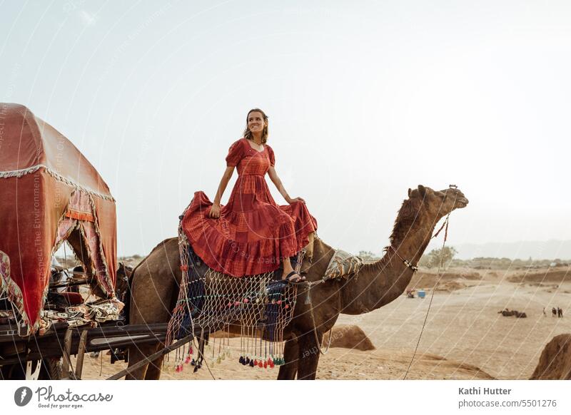 eine junge Frau sitzt in einem langen, roten Kleid auf einem Kamel in der Wüste schön Junge Frau Jugendliche Lifestyle Mädchen Porträt Fröhlichkeit