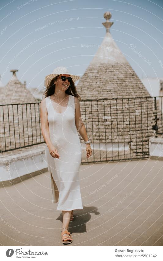 Eine junge Frau in einem weißen Kleid und einem Hut während eines Touristenbesuchs in Alberobello, Italien Architektur hübsch Menschen Mode Lifestyle Aktivität
