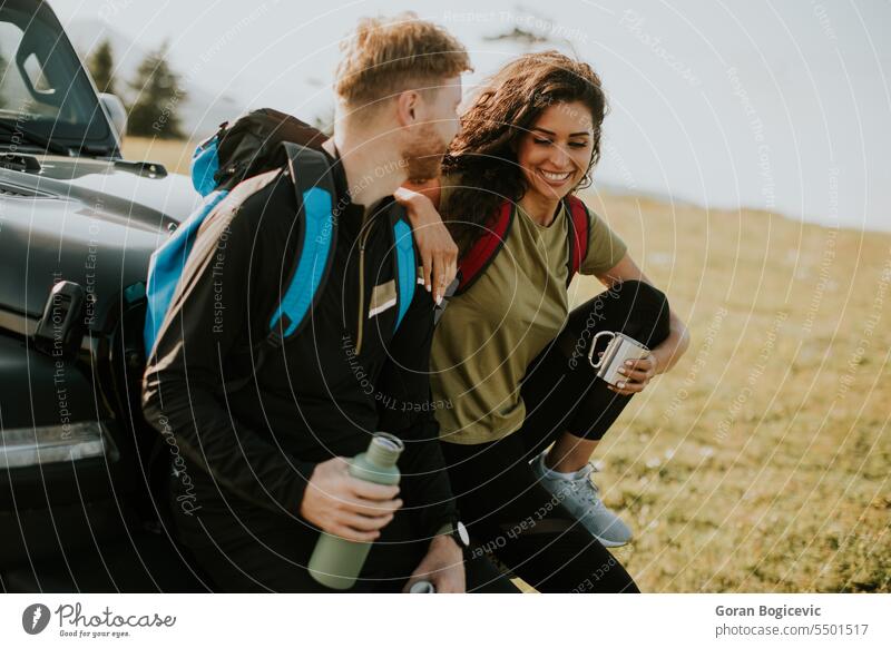 Junges Paar entspannt sich auf der Motorhaube eines Geländewagens auf dem Lande Erwachsener Abenteuer attraktiv Auto Automobil Pause Windstille PKW Kaukasier