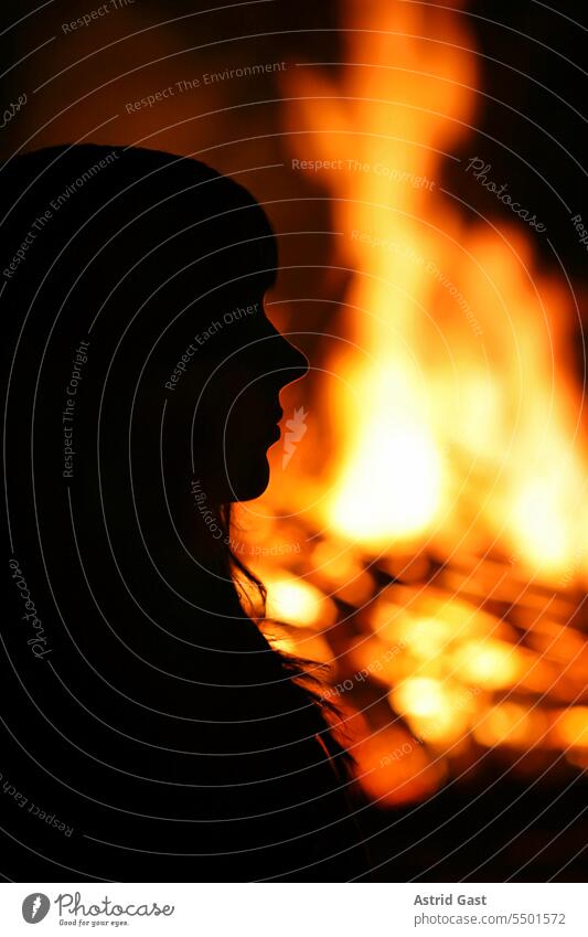 Eine junge Frau steht vor einem großen Feuer feuer brennen brand funken funkenfeuer osterfeuer brennstoff hitze brauch fasching holz sitte hexenverbrennung