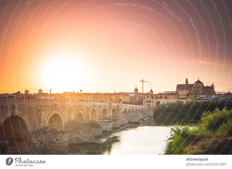 Blick entlang der römischen Brücke in Cordoba zum Sonnenuntergang Spanien Andalusien Römische Brücke Fluss Flussufer Guadalquivir Sommer Sommerurlaub Abendrot