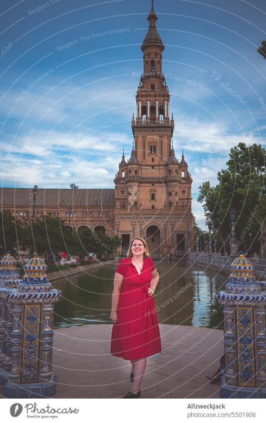 Frau mittleren Alters mit blonden Haaren und rotem Kleid auf dem Plaza de España Spanien Andalusien Sevilla rotes kleid Wasser blondes Haar Blondine Urlaub