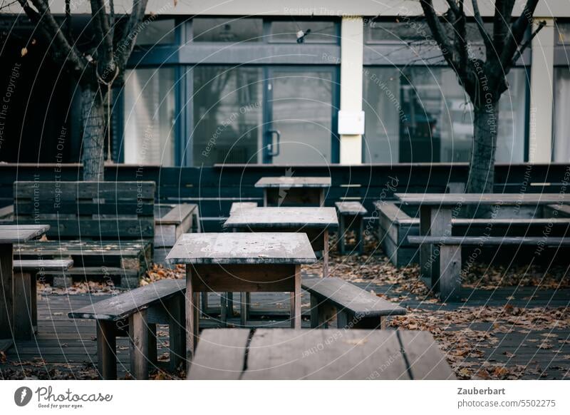 Leere Tische und Bänke im Außenbereich einer Gaststätte mit moderner Fassade im Herbst Cafe verlassen leer dunkel kalt Saison vorbei geschlossen Gastronomie
