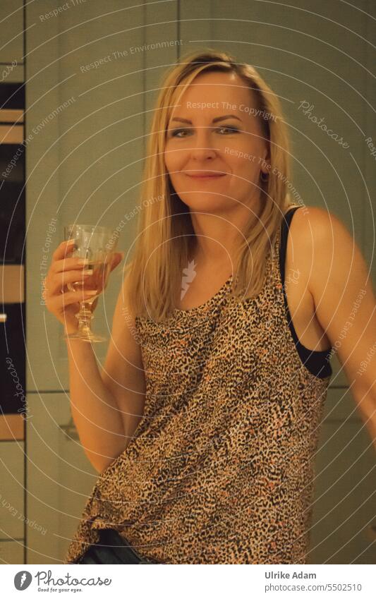 Drinkje bej Inkje | Partylaune - Frau steht locker mit einem Glas Wein in der Hand in der Küche und schaut in die Kamera positiv frech Gute Laune Wohlgefühl