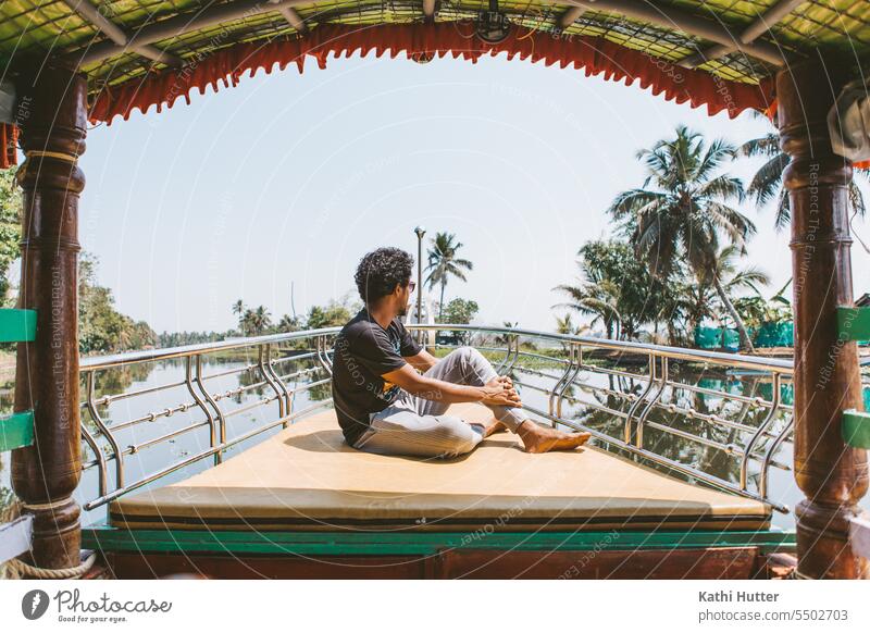 ein junger Mann sitzt auf dem Bug eines Bootes in den Backwaters von Alappuzha Bootsfahrt Wasserfahrzeug Ferien & Urlaub & Reisen Ausflug Meer Farbfoto