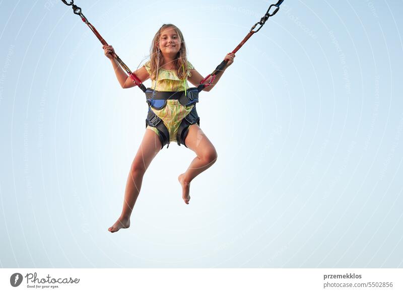 Bungee-Springen auf dem Trampolin. Kleines Mädchen hüpft auf Bungee-Springen im Vergnügungspark auf Sommerferien springend Vergnügen Park Ferien Spielen spielen