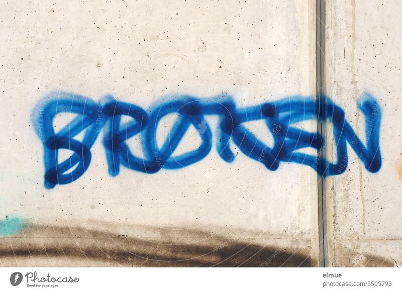 BROKEN steht in blauer Schrift an einer Betonwand broken gebrochen kaputt Gamersprache Jugendsprache zerbrochen ruiniert Graffiti Design unfair fehlerhaft