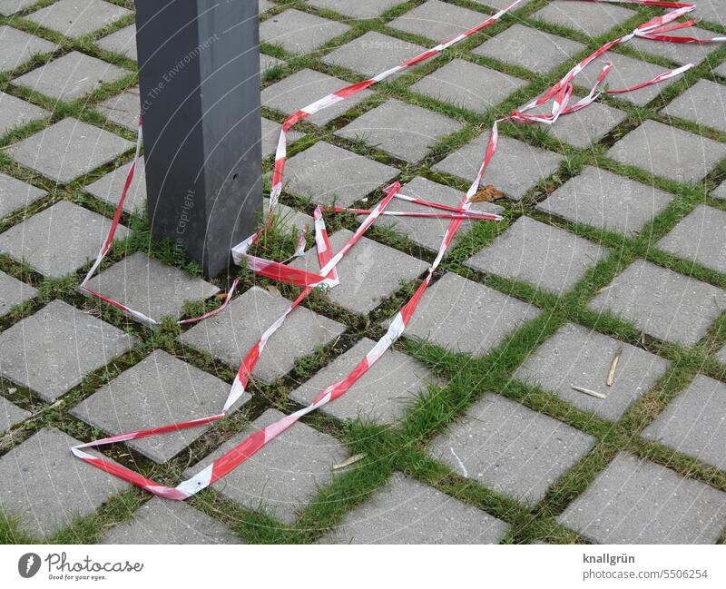Absperrband Flatterband rot-weiß Sicherheit Schutz Absperrung Prävention Menschenleer Boden Muster Quadrate kariert Pfosten Gras grau grün Außenaufnahme
