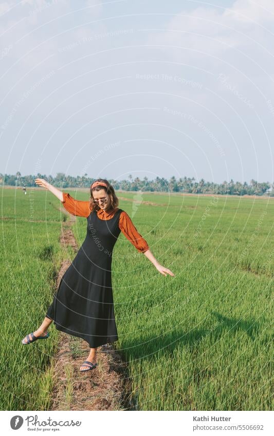 eine junge Frau steht einem Reisfeld in Kerala. Sie trägt ein schwarzes langes Kleid und eine rote Blouse. modern schön Person Mädchen Porträt Erwachsener Model