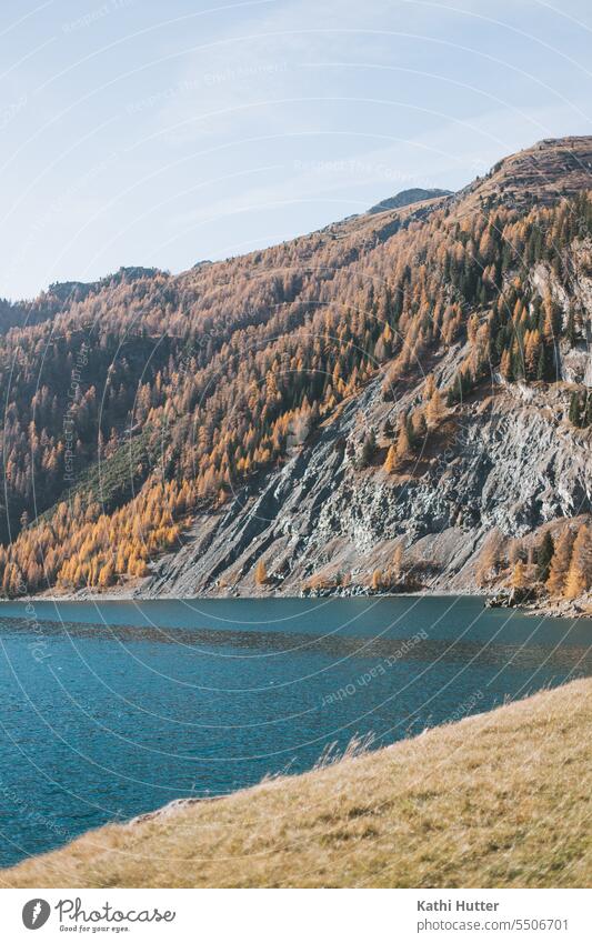 ein blauer See mit einem Berg im Hintergrund der viele Tannenbäume in herbstlichen Farben hat. Bergsee Natur Landschaft Berge u. Gebirge Außenaufnahme Wasser