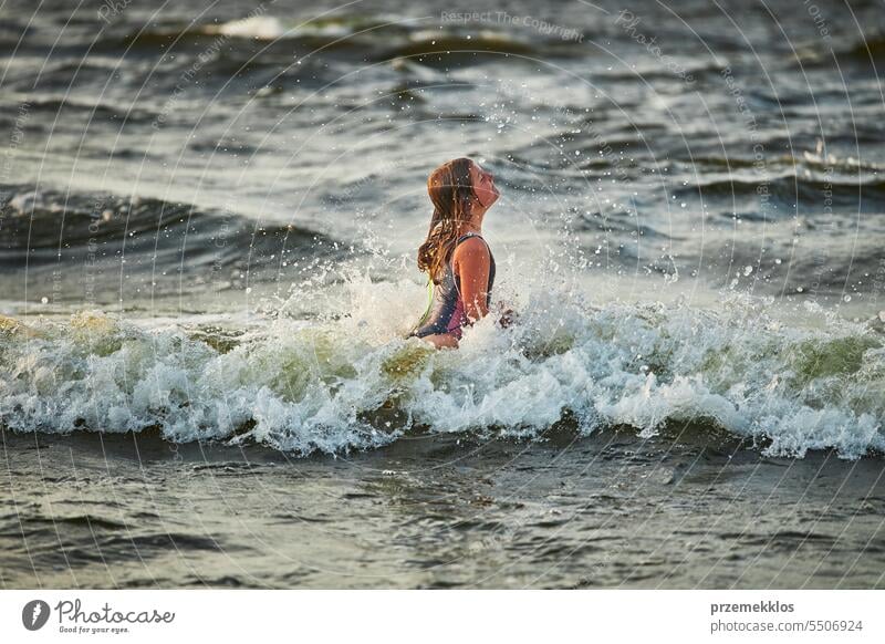 Kleines Mädchen spielt mit Wellen im Meer. Kind plantscht spielerisch mit Wellen. Kind springt in Meereswellen. Sommerurlaub am Strand Ferien MEER Spielen