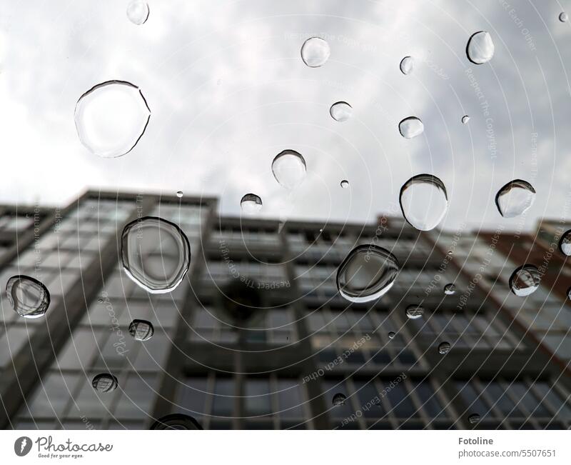 Durch eine vollgetropfte Scheibe nach oben schauen und das Grau der Stadt noch etwas spannender sehen. Tropfen Wasser Wassertropfen Regen nass Nahaufnahme