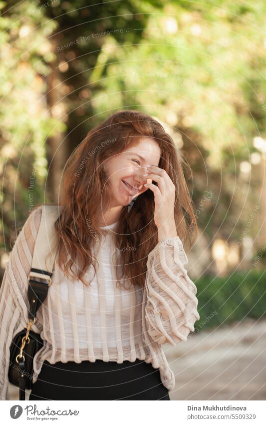 candid Porträt der jungen schönen Frau lachend mit Sonnenlicht im Hintergrund im Sommer. Hübsches rothaariges Mädchen mit roten Haaren. lauhging Park Lächeln