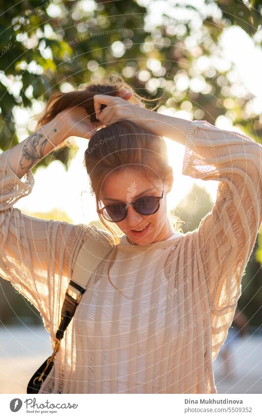 candid Porträt der jungen schönen Frau mit Sonnenbrille im Gegenlicht mit Sonnenlicht im Sommer. Hübsches rothaariges Mädchen mit roten Haaren. Park Lächeln