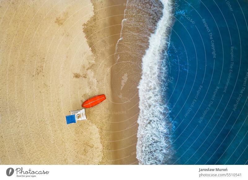 Luftaufnahme der Ostseeküste mit Wellen, die den Sandstrand während des Sonnenaufgangs am Morgen zermalmen, Rettungsschwimmerposten und Boot, Drohnenfotografie