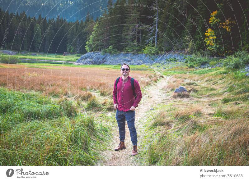 Mann mittleren Alters mit Sonnenbrille und rotem Hemd steht in der Natur in Montenegro Urlaub Urlaubsstimmung Naturschutzgebiet wandern Erholung Wiese Gras