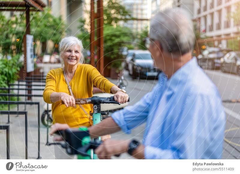 Ein älteres Paar fährt mit einem Elektroroller durch die Stadt Menschen Kaukasier Stehen Gesundheit Stadtleben graues Haar genießen Straße lässig Tag Porträt