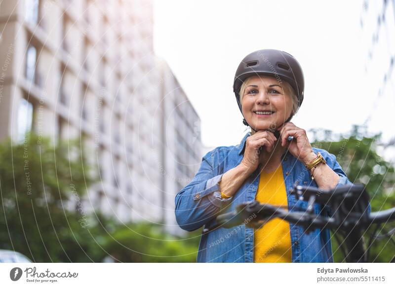 Porträt einer älteren Frau mit Helm beim Fahrradfahren in der Stadt Menschen Kaukasier Stehen Gesundheit Stadtleben graues Haar genießen Straße lässig Tag