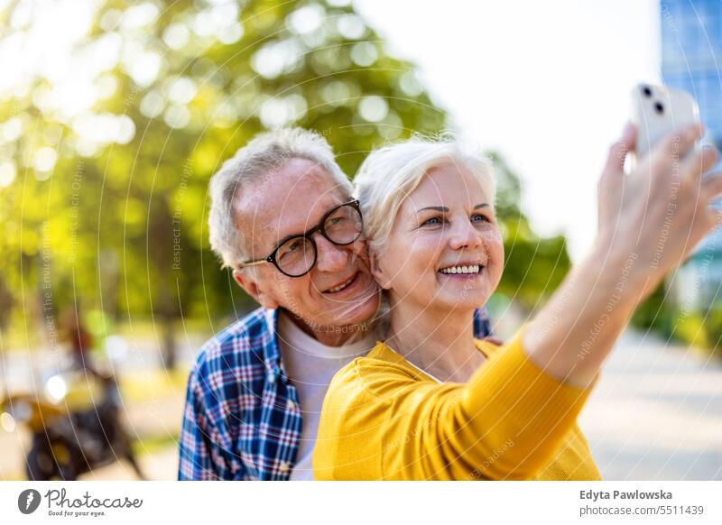 Älteres Paar nutzt Smartphone in der Stadt Menschen Kaukasier Stehen Gesundheit Stadtleben graues Haar genießen Straße lässig Tag Porträt außerhalb