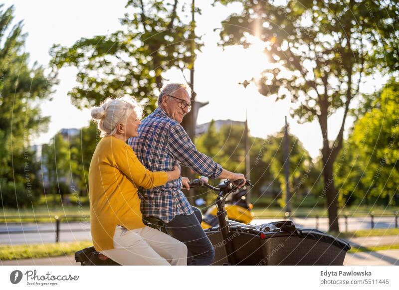Älteres Paar fährt mit dem Lastenrad in der Stadt Menschen Kaukasier Stehen Gesundheit Stadtleben graues Haar genießen Straße lässig Tag Porträt außerhalb