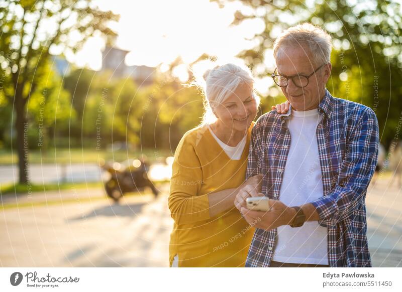 Älteres Paar nutzt Smartphone in der Stadt Menschen Kaukasier Stehen Gesundheit Stadtleben graues Haar genießen Straße lässig Tag Porträt außerhalb
