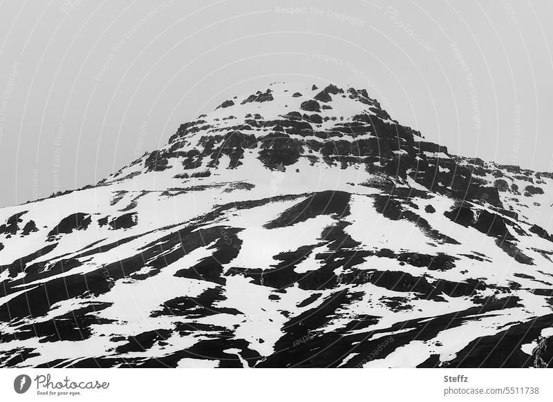 Blick auf einen Berg mit Schneeflecken auf Island isländisch Islandreise Islandbild isländische Landschaft Hügel Schneeschmelze Schneeformen verschneit Felsen