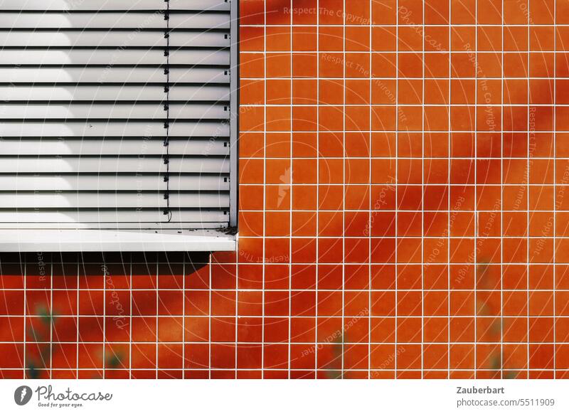 Fassade mit orangen, quadratischen Fliesen und geschlossener Jalousie minimalistisch geometrisch Form Struktur Architektur abstrakt modern Muster