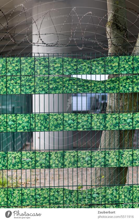 Stadtlandschaft, Bauzaun mit Stacheldraht und grünem Fake-Laub, dahinter Beton-Pfeiler einer Brücke Landschaft fake Illusion KI gau versperrt Baum falsch