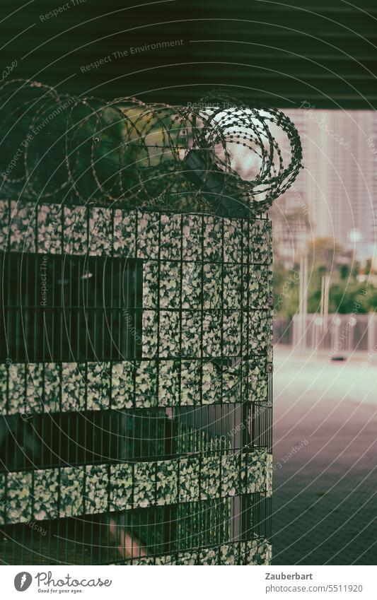 Stadtlandschaft im Film-Look, Bauzaun mit Stacheldraht und grünem Fake-Laub, dahinter Beton-Pfeiler einer Brücke Movie Landschaft beängstigend fake Illusion KI