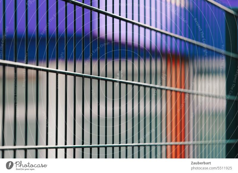 Zaun in Perspektive, dahinter unscharfe Strukturen in blau und rot Metall Flucht Stadt gefangen eingefangen unwirtlich unwirklich Barriere Grenze Schutz