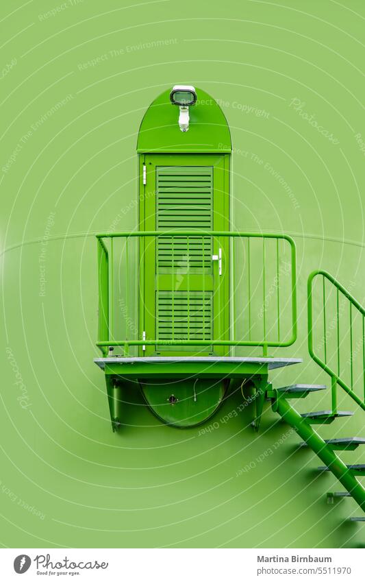 Industrielle Metalltür und Treppe, die zu einer grün gestrichenen Windmühle hinaufführt Tür Eingang industriell Sonnenuntergang Energie Treppenhaus Konstruktion