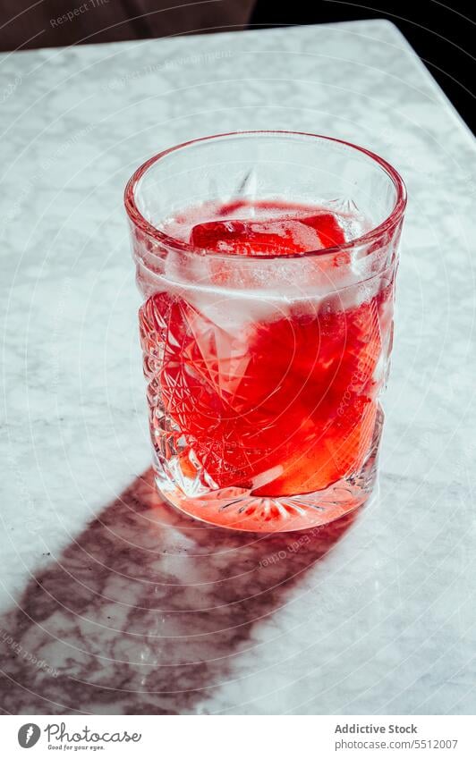 Ein Glas kaltes rotes alkoholisches Getränk Cocktail Alkohol trinken Erfrischung Eis Würfel sprudeln liquide Tonic Murmel Schaumblase Limonade