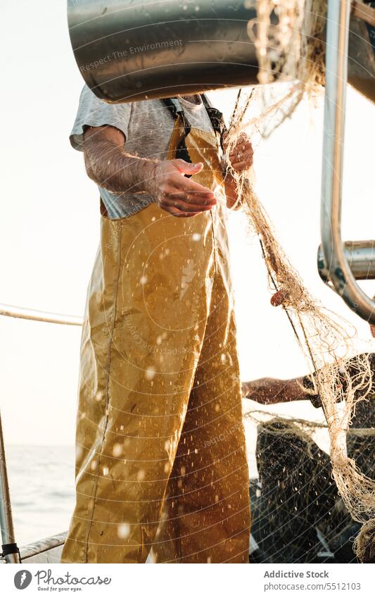 Anonymer Fischer, der vom Segelboot aus im offenen Meer fischt Boot MEER Fischen Netz Schoner Arbeit Uniform Fokus männlich Soller Balearen Mallorca Wadenfisch