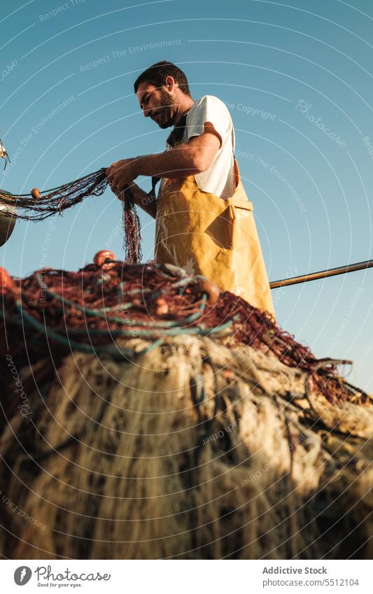 Mann, der ein Netz aus einem Segelboot im Meer zieht Fischer ziehen Fischen aufbinden Boot Trawler Schürze männlich Soller Balearen Mallorca Wadenfisch jagen