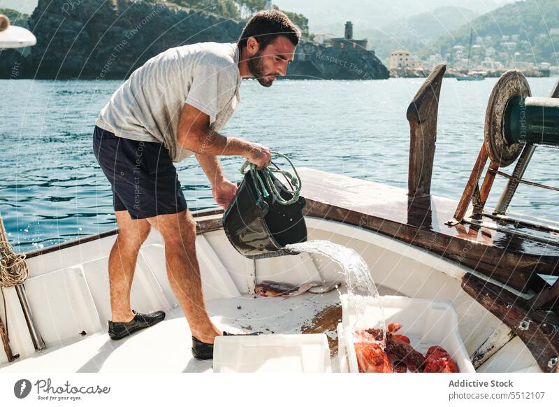 Hispanischer Mann gießt Wasser aus einem Eimer Fischen Boot eingießen Fischer ernst Kasten männlich Soller Baleareninsel Mallorca hispanisch ethnisch Container
