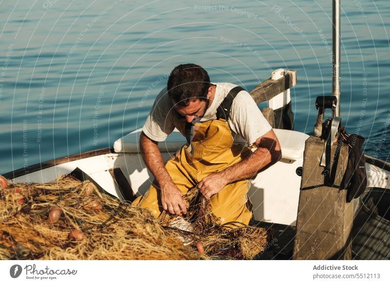 Fischer knüpft Netz auf Segelboot im Meer auf - ein lizenzfreies