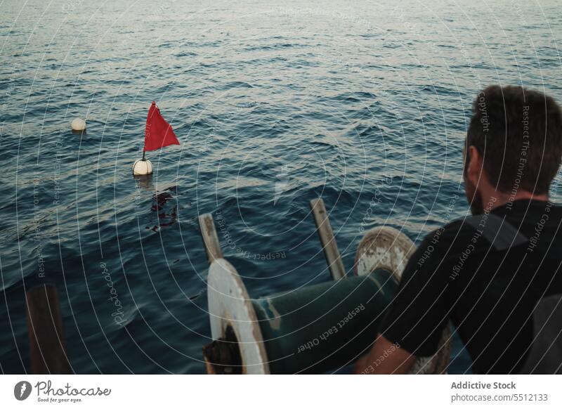 Unbekannter Mann steht auf einem Boot und schwimmenden Bojen im Meerwasser Fahne Lebensretter Schwimmer Rippeln Gefäße Rad MEER männlich Rettungsschwimmer