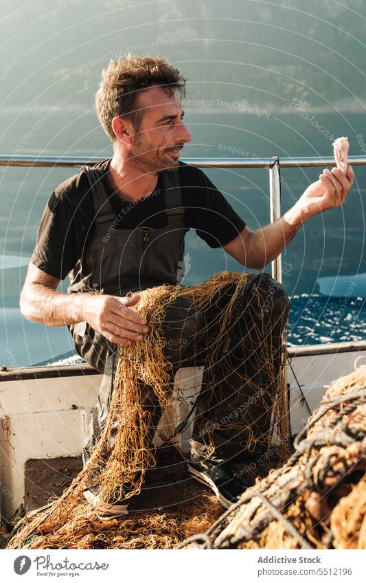 Seemann sammelt gefangene Meeresfrüchte aus dem Netz auf See Fischer Jakobsmuschel abholen pflücken Tradition Fischen männlich Soller Balearen Spanien Mallorca